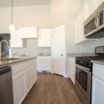 Spacious modern kitchen with white cabinets and stainless steel appliances.