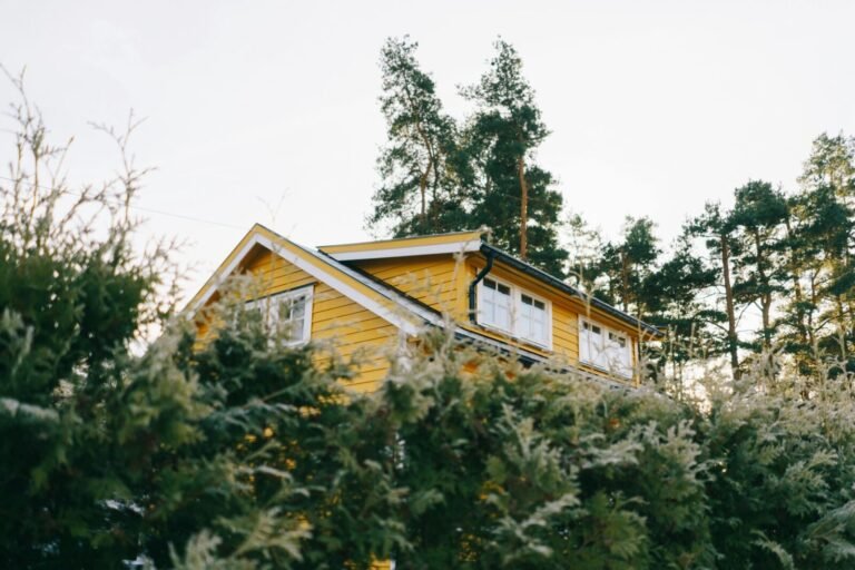 A picturesque yellow house surrounded by lush green trees, ideal for country living.